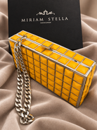 Clutch rigida gialla con motivo geometrico e catena argentata