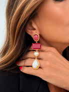Orecchini pendenti fucsia con effetto perla e goccia bianca indossati